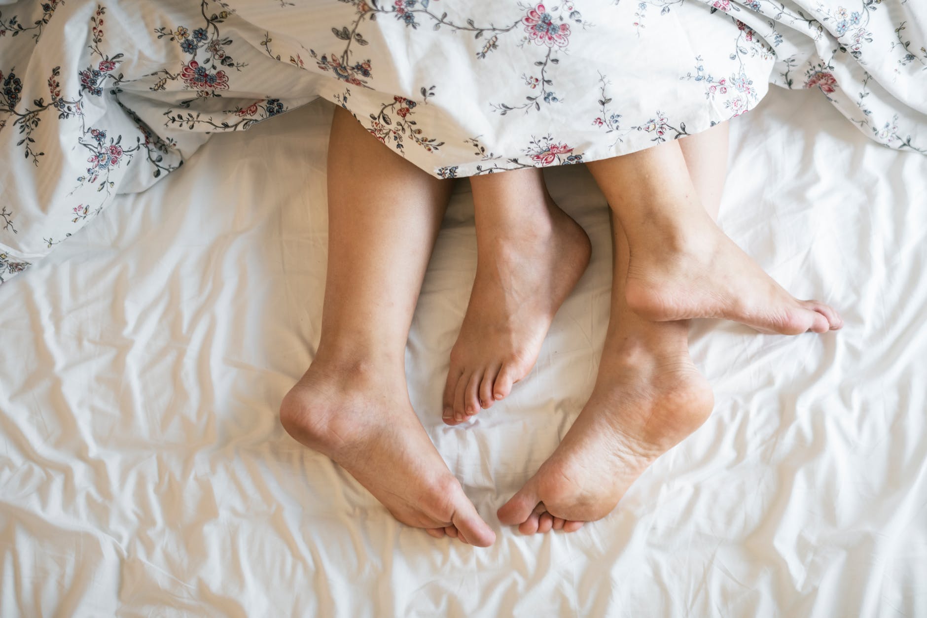 two people laying on a bed covered with a floral comforter